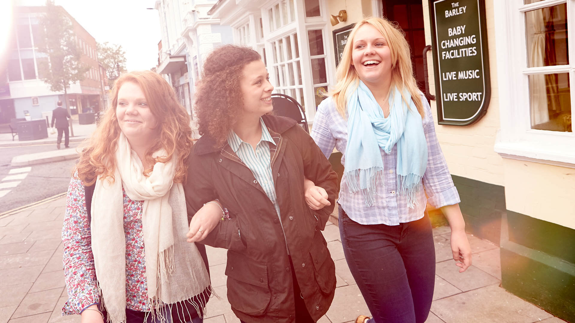 Three female students walk down Newport High Street in the sunshine